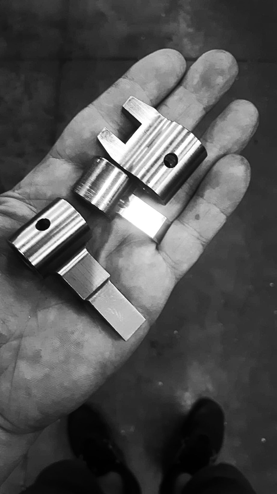 Componenti fresati in alluminio, tenuti in mano dopo la lavorazione CNC
