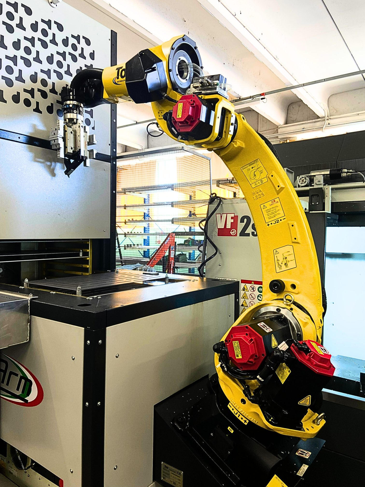 Braccio robotizzato giallo del magazzino affiancato al centro CNC